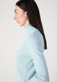 Lichtblauwe lange mouwen turtleneck trui met een gerimpelde kraag, gemaakt van zachte stof, met een aansluitend ontwerp en zichtbare naaddetails.