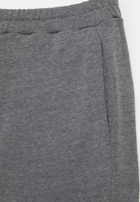 Pantalon de survêtement en tissu gris doux avec taille élastique et poche latérale visible sur fond blanc.