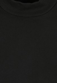 Svart ribbad crew neck-tröja som visar detaljerad stickad textur och krage-sömmar.