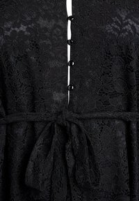 Čierne čipkované šaty s kvetinovými motívmi, zapínaním na gombík pri krku a zaväzovaním v páse pre priliehavý vzhľad.