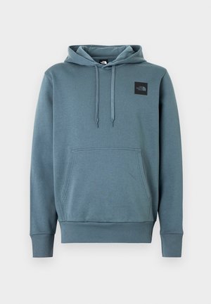 Bluza z kapturem w stłumionym niebiesko-szarym odcieniu, wykonana z miękkiego materiału. Posiada przednią kieszeń oraz małą czarną naszywkę z logo na piersi.