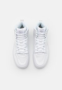 Zapatillas altas blancas de cuero, con detalles perforados, cordones planos y una etiqueta en la lengua con el logo de Lacoste.