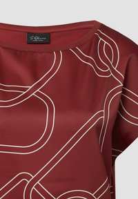 Bordeauxfarbige Bluse mit rundem Ausschnitt, verziert mit weißen, abstrakten Linienmustern. Hergestellt aus glattem Stoff mit leicht glänzender Textur.