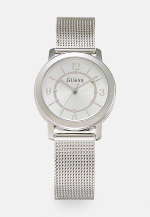 Zegarek na srebrnej siateczkowej bransolecie z okrągłą, srebrną kopertą. Biała tarcza z oznaczeniami godzinowymi na 12, 3, 6 i 9 oraz logo "GUESS".