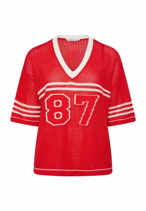 Roter kurzärmeliger Strickpullover mit weißem V-Ausschnitt, weißen Streifen an den Ärmeln und großer, weiß umrandeter Zahl "87" auf der Vorderseite.