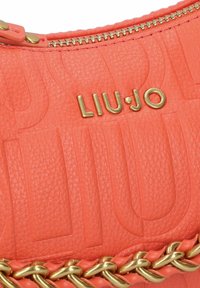 Sac à main en cuir texturé corail avec une fermeture éclair dorée, arborant un logo doré « LIU·JO » et un accent décoratif en chaîne dorée à la base.