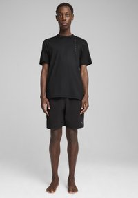 Sort, svedtransporterende atletisk t-shirt med korte ærmer, parret med sorte shorts med et logo, begge lavet af letvægtsstof.