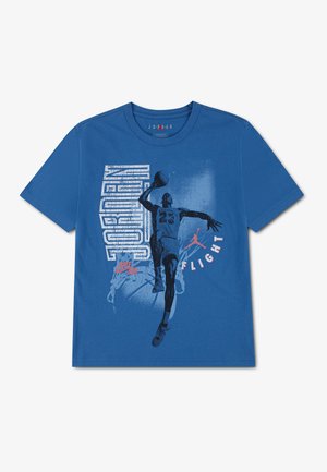 Niebieska koszulka z grafiką koszykarza robiącego wsad, słowo "JORDAN" pionowo, logo Nike i słowo "FLIGHT" białymi literami.