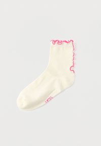 Βαμβακερό αστραγάλιο καλτσάκι σε εκρού χρώμα με ροζ βολάν στην κορυφή και ροζ λογότυπο στο πλάι. Μαλακή υφή και ελαστική εφαρμογή.