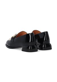 Zwarte patenten leren schoenen met een lage, stevige hak, met een contrasterende lichtgekleurde accent en een decoratieve gesp aan de voorkant.