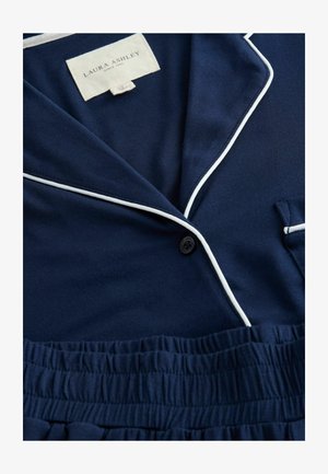 Mornarska pižama s belimi robovi, ki vključuje ovratnik s klini, enojno zaponko in elastičen pas. Gladka tekstura tkanine.