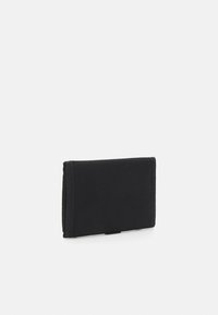 Portefeuille en tissu noir de forme rectangulaire, avec une surface texturée et des bords surpiqués, présentant un design simple et sans ornement.
