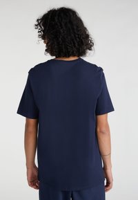 Camiseta de algodón azul marino con mangas cortas, escote redondo y corte recto. Textura suave, diseño minimalista, sin logos ni patrones visibles.