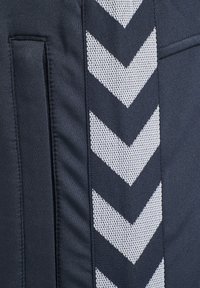 Navy athletic shorts with a textured white chevron design along the side, featuring a smooth fabric finish and a side pocket detail.