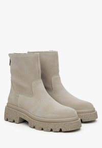 Beige suède enkellaarsjes met een robuuste, gestructureerde platformzool. Voorzien van gestikte zijkanten en een trekband aan de achterkant voor gemakkelijk aantrekken.
