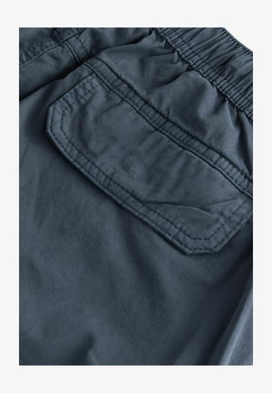 Shorts de tejido azul marino oscuro con cintura elástica, pliegues laterales y un bolsillo trasero con parche y detalles de costura en contraste.