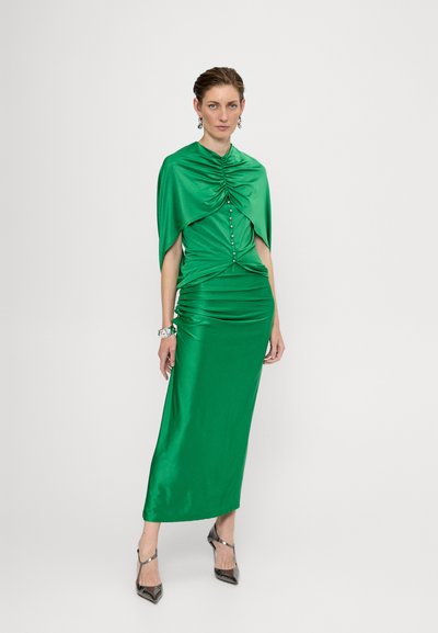 Grøn satin kjole med en draperet, samlet bærestykke, knapdetaljer og en lang nederdel. Kombineret med sølvfarvede hæle og accessories.