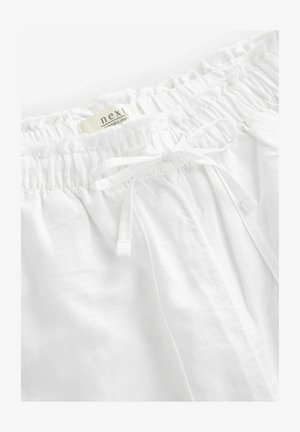 Pantaloni corti bianchi in lino con cintura elastica e cordoncino. Tessuto morbido e leggero con una sottile texture. Etichetta del marchio visibile.