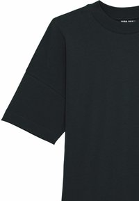 Camiseta negra de manga corta hecha de algodón suave, con un cuello redondo clásico y un corte relajado. Presenta costuras en las mangas y el dobladillo.