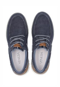 Marineblaue Segeltuchschuhe mit weißer Sohle, ausgestattet mit kontrastierenden Schnürsenkeln, Lederakzenten und einem Logodetail auf der Innensohle. Rundes Zehendesign.