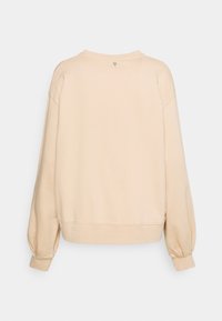 Sudadera de color beige claro con un corte relajado. Presenta mangas largas con puños fruncidos y un pequeño detalle de logo en la parte posterior del cuello. Textura suave.