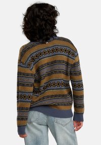 Strickpullover in Braun, Blau und Creme mit geometrischen Mustern. Mit gerippten Bündchen und Saum. Lockere Passform, gemusterte Textur im gesamten Kleidungsstück.