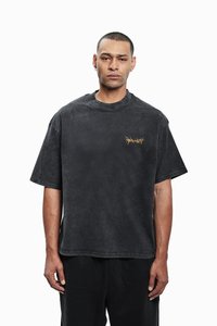 Overdimensjonert svart bomulls-T-skjorte med rund hals og korte ermer. Har en liten gul torn-grafikk på brystet.