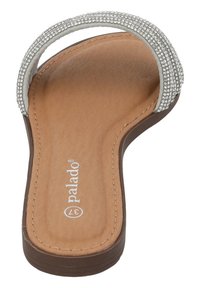 Sandalo piatto con un plantare in finta pelle color tan, una cinturino di strass argento e una suola in gomma testurizzata marrone. Presenta una forma sagomata.