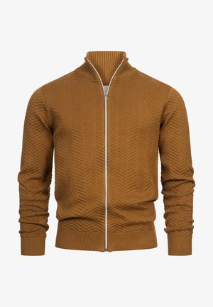 Ruskea vetoketjullinen neuletakki, joka on valmistettu teksturoidusta neulekankaasta. Sen ominaisuuksiin kuuluvat korkea kaulus sekä ribbaatut hihansuut ja helma, jossa on chevron-kuvio.