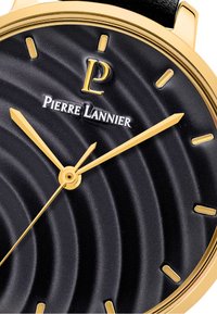 Rund klocka med en svart texturerad urtavla som har guldfärgade timmarkeringar och visare. Logotypen "Pierre Lannier" visas ovanför mitten.