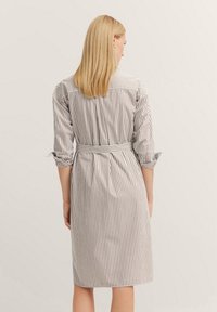 Gestreiftes Hemdkleid mit Dreiviertelärmeln, am Taillenbereich gerafft, mit vertikalen marineblauen und weißen Streifen, knielange.