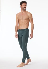 Grüne, figurbetonte Leggings aus weichem Stoff mit einem weißen Seitenstreifen und einem elastischen Bund. Glatte Textur und knöchellanges Design.