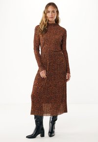 Leopardenmuster Kleid in Brauntönen, mit langen Ärmeln und einem plissierten Rock. Tragen mit schwarz spitzen Stiefeln für den Kontrast.