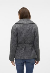 Manteau texturé gris avec un large col et une taille ceinturée, doté de manches longues et d'une coupe décontractée. La vue de dos montre une construction en tissu robuste.