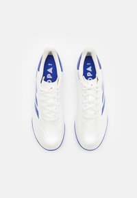 Scarpe da ginnastica bianche con accenti blu, materiale sintetico liscio, punta rotonda, lacci piatti e suola sagomata. Contrassegnate dal logo "Copa" sulla linguetta.