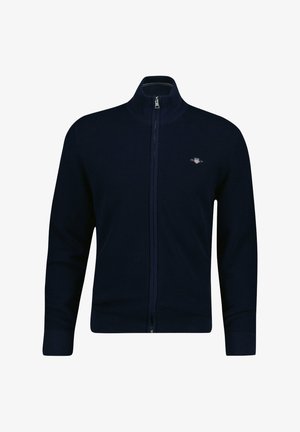 Pull zippé bleu marine en tissu tricoté texturé, avec col montant et poignets côtelés. Logo discret sur le côté supérieur gauche.