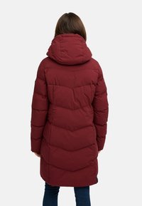 Bordo pūkų paltas su kapišonu, su siuvinėtu dizainu, ilgomis rankovėmis ir vidutinio ilgio iki šlaunų, matomais siūlais ir šoninėmis kišenėmis.