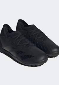 Svarta sportskor med ett strukturerat syntetiskt överdel, som har upphöjda perforeringar, traditionell snörning och en gummisula med dobbar.