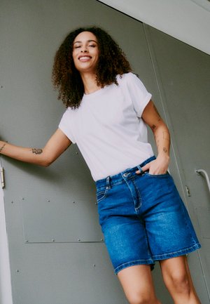 Hvit bomulls t-skjorte og blå denimshorts. Shortsene har rett passform, fem lommer og en lett slitt kant.