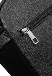 Borsa in pelle nera con superficie testurizzata, dotata di un tirante in metallo e apertura liscia. Il design si concentra sulla funzionalità e sulla semplicità.