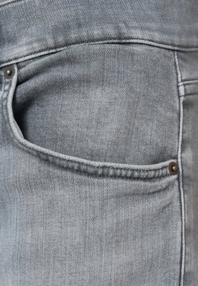Ανοιχτό γκρι τζιν παντελόνι από denim με πίσω τσέπη που διαθέτει ραφές λεπτομέρειες και μεταλλικό διακοσμητικό καρφί. Η υφή φαίνεται λεία με διακριτική ξεθώριασμα.