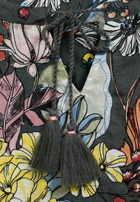Floral patterned fabric with shades of gray, pink, yellow, and green. Features two gray tassels with pink accents at the neckline.