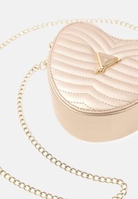 Hartvormige, gewatteerde metallic roze tas met gouden hardware en kettingband. Heeft een logo-accent aan de voorkant. Soepele textuur.