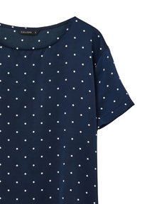 Maglietta blu navy a maniche corte con pois bianchi, realizzata in un tessuto liscio. Presenta un collo rotondo e una vestibilità morbida. Etichetta del marchio visibile.