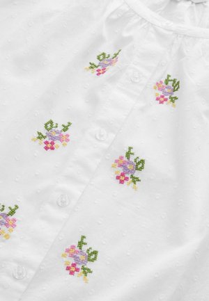 Camicia bianca in tessuto testurizzato. Presenta piccoli motivi floreali ricamati in rosa, viola, giallo e verde. Bottoni in plastica trasparente.