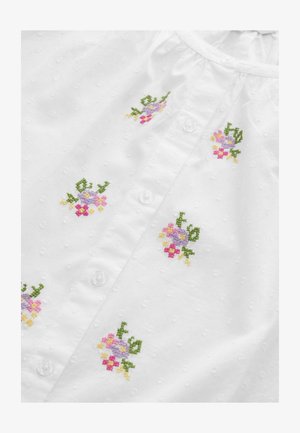 Camicia bianca in tessuto testurizzato. Presenta piccoli motivi floreali ricamati in rosa, viola, giallo e verde. Bottoni in plastica trasparente.