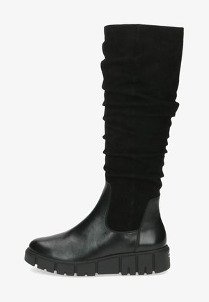 Botas negras hasta la rodilla con un upper de ante arrugado y una puntera de cuero liso. Presentan una suela negra robusta con un grueso dibujo para la estabilidad.