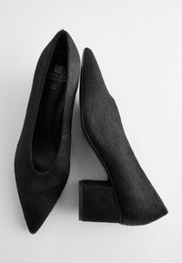 Svarta kvinnoskors spetsiga skor med klossklackar, med en mjuk texturerad yta och "Forever Comfort"-märkning inuti.