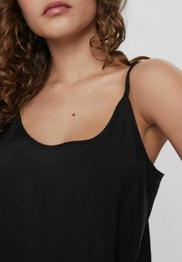 Top negru fără mâneci, cu bretele subțiri, decolteu rotund și o textură moale, ușoară. Design simplu, fără modele sau accente vizibile.
