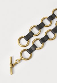 Bracciale in catena di link in pelle nera, caratterizzato da grandi anelli dorati, chiusura a toggles e dettagli in rilievo sul logo sugli accenti circolari.